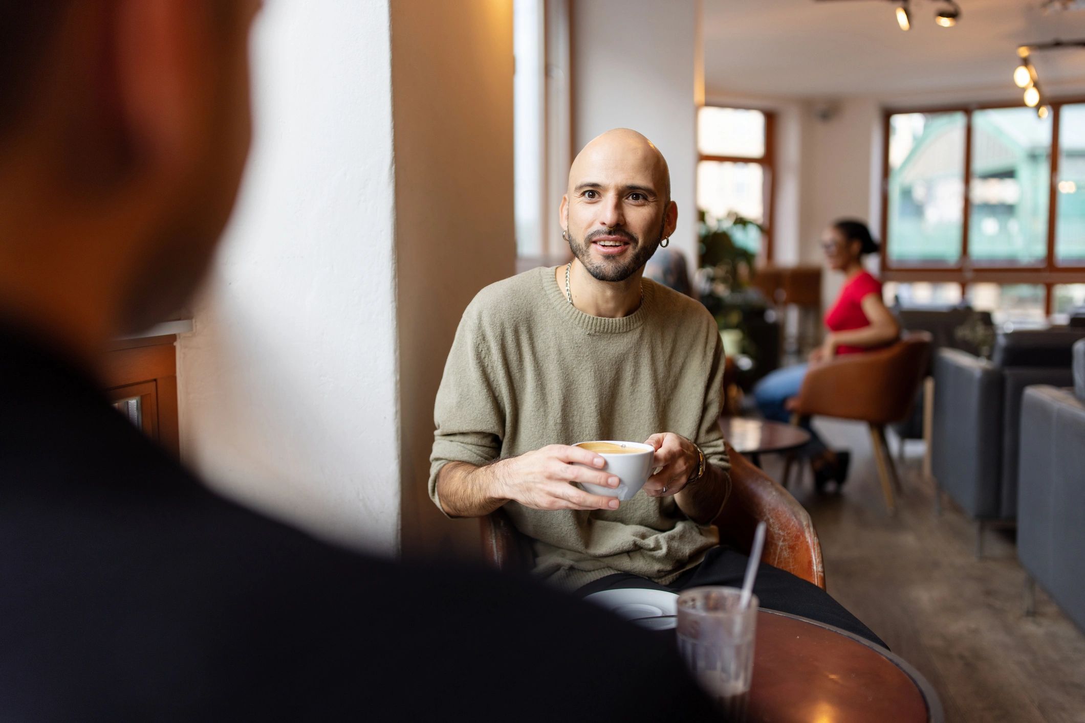 Smiling man holding a coffee cup at a cafe table