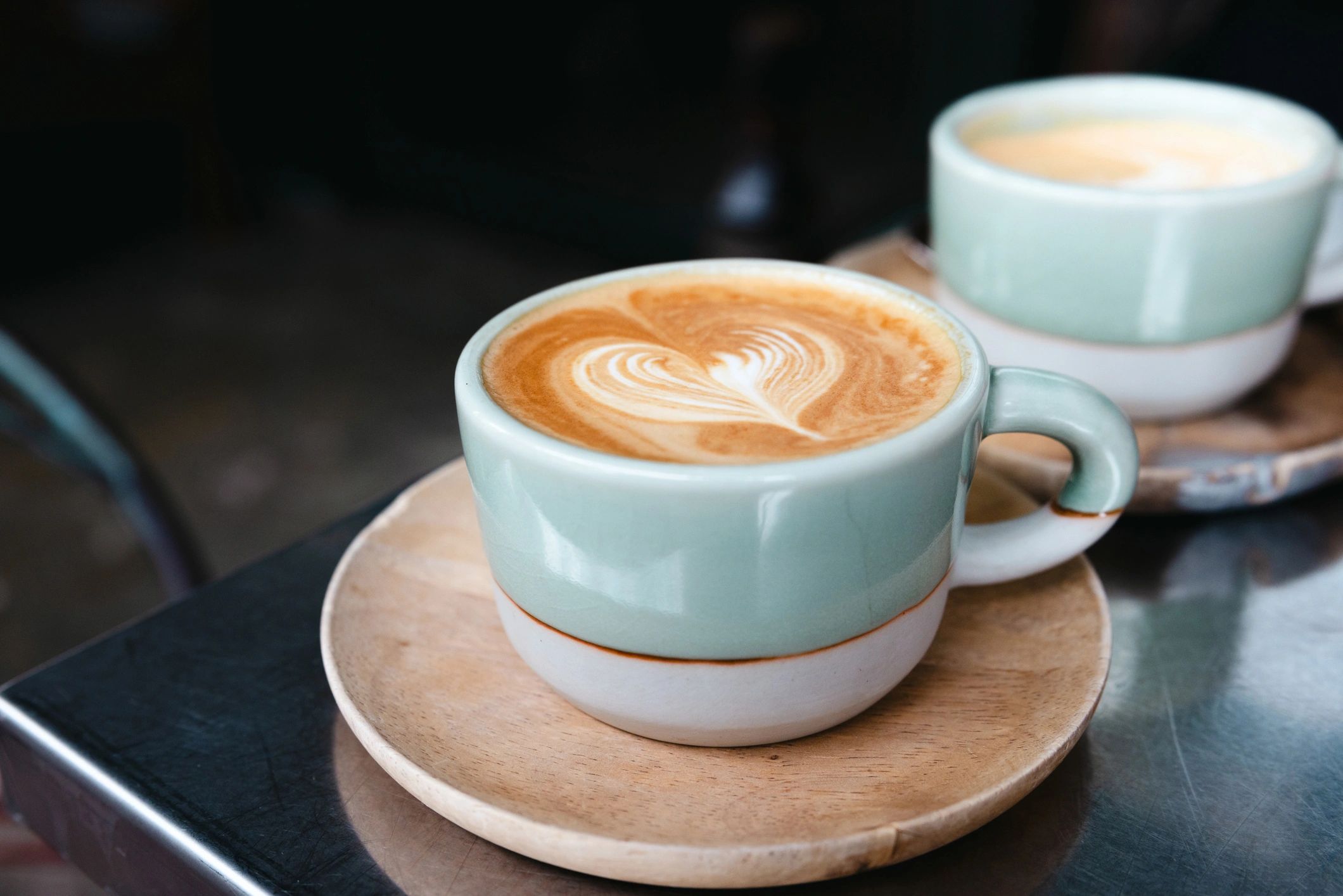 Flat white coffee in a green mug on a cafe table
